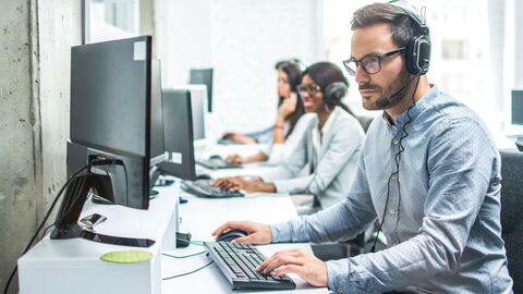 Eine Reihe von Schreibtischen mit Dolmetscherinnen und Dolmetschern bei der Arbeit