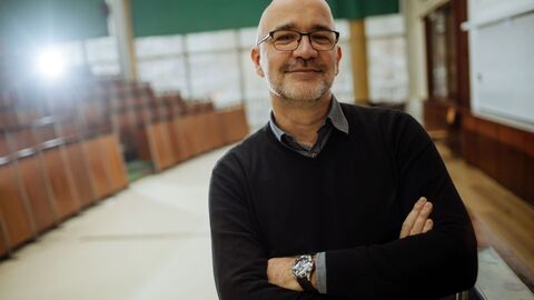 Bild zum Thema Lehrer in einem Hörsaal, der den Betrachter anschaut.