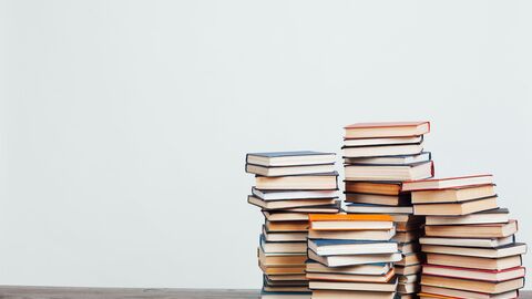 Bild zum Thema Vier Stapeln mit Büchern vor einer puristischen Wand