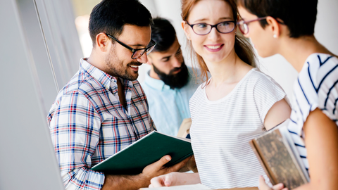 Bild zum Thema Eine Gruppe von Lehrerinnen und Lehrern im Gespräch; in der Hand Bücher