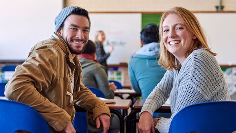 Bild zum Thema Eine Seminarraum mit Teilnehmern; ein junger Mann und eine junge Frau drehen sich dem Betrachter zu um