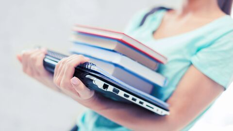 Bild zum Thema Eine Frau, die ein Notebook und einen Stapel Bücher trägt