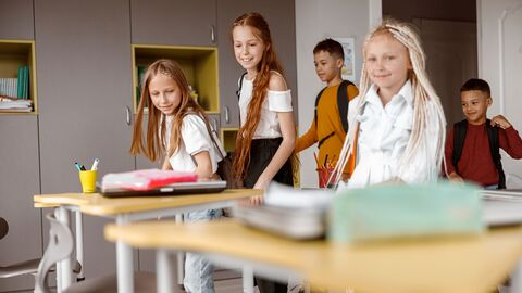 Bild zum Thema Schüler, die gerade in das Klassenzimmer zu ihren Tischen kommen