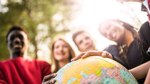 Jugendliche in der Natur, die ihre Hände auf einen großen Erdball legen 