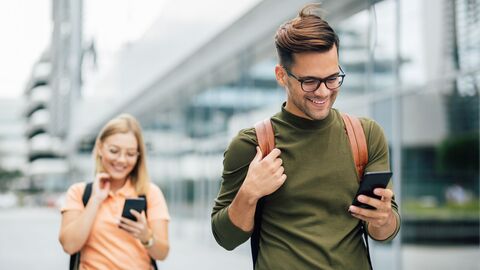 Bild zum Thema Zwei Studenten vor dem Unigebäude, die gerade mit ihren Handys telefonieren