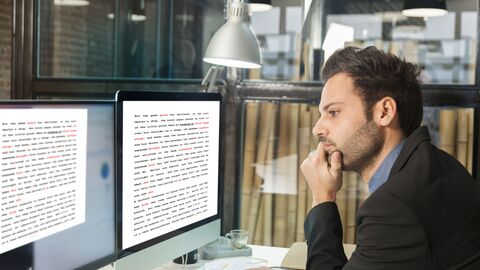 Ein Übersetzer bei der Arbeit; vor ihm zwei Monitore mit Texten