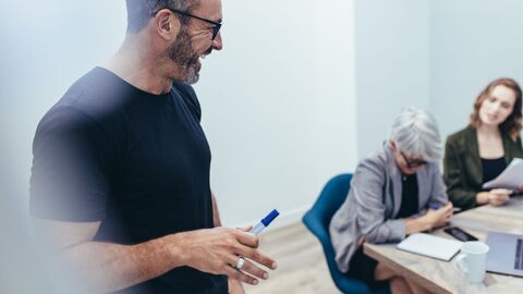 Bild zum Thema Lehrkräfte bei einer Fortbildung; der Trainer steht vor der Gruppe mit einem Stift in der Hand