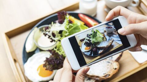 Kennbild zum Tag der Ernährungsbildung Ein Handy, mit dem gerade eine Teller mit einem leckeren Gericht fotografiert wird