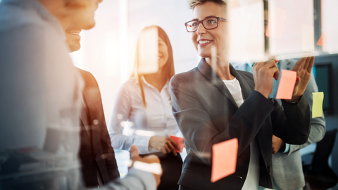Eine Frau, die mit einem Team etwas in einem Büro bespricht