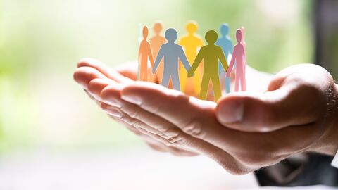 Bild zum Thema Zwei Hände, die einen Kreis aus bunten Papier-Menschen umfassen