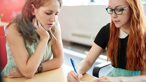 Interne Evaluation Zwei Schülerinnen beim Ausfüllen eines Feedback-Bogens