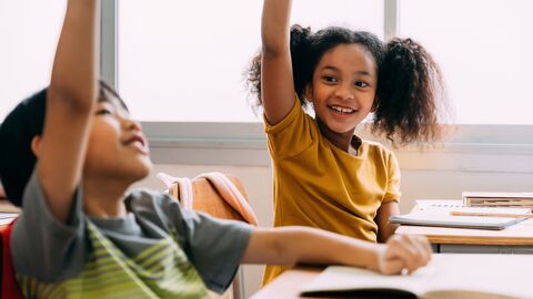 Mathe in der Grundschule Ein Schüler und eine Schülerin im Unterricht, die sich gerade melden