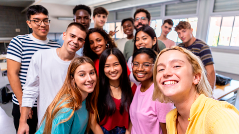 Eine Gruppe internationaler Jugendlicher in einem Klassenzimmer, die gerade ein Selfi machen
