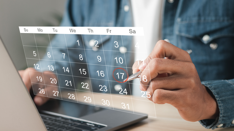 Kalender Eine Person, die vor einem Notebook sitzt und etwas in einem virtuellen Kalender notiert