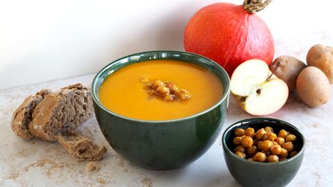 Kürbiscremesuppe mit gerösteten Kichererbsen und einigen Zutaten im Hintergrund