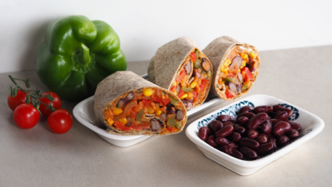 Bunte veggie Burritos mit einigen Zutaten im Hintergrund