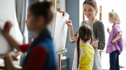 Lehrerin im Kunstunterricht; die Klasse malt
