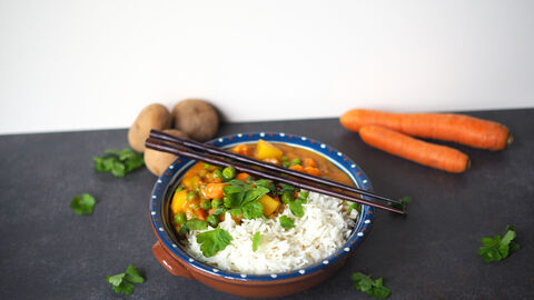 Buntes Gemüsecurry mit einigen Zutaten im Hintergrund