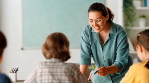 Eine Lehrerin erklärt einer Gruppe Schülern etwas mithilfe eines Stiftes