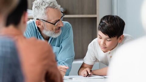 Ein Lehrer sitzt neben einem Schüler und erklärt etwas