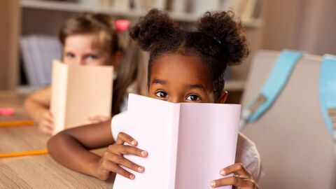 Schulkinder, die sich hinter Büchern verstecken