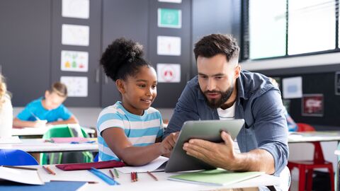 Ein Lehrer erklärt einer Schülerin etwas am Tablet