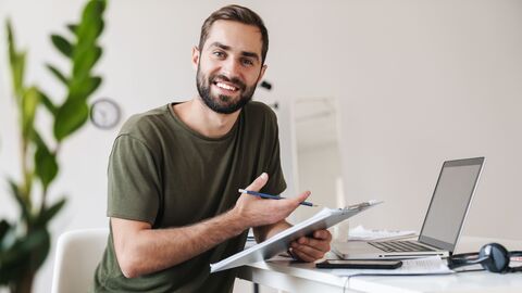 Junger Lehrer vor Notebook mit Notizen in der Hand