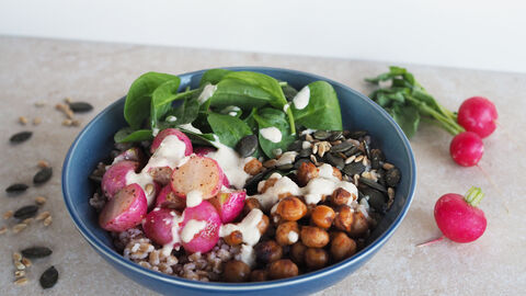 Auf dem Bild sieht man eine Schale in der eine Bowl mit Radieschen, Babyspinat, Kichererbsen, Sonnenblumenkernen und weiteren Zutaten bereitet wurde.