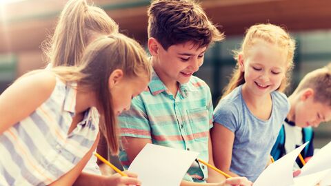 Ethikunterricht Fünf Schüler mit Papier und Stiften im Gespräch