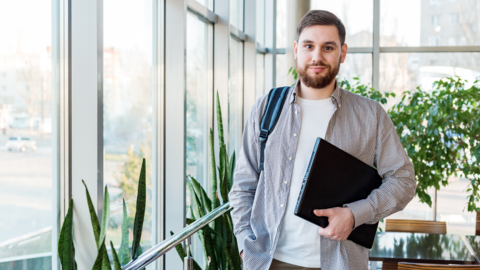 Praktika im Lehramtsstudium Student mit Notebook unter dem Arm in einem Büro
