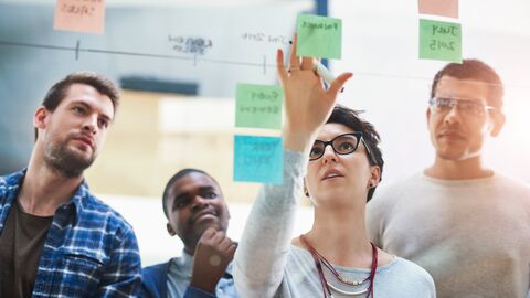Lehrkräfte, die vor einer Wand mit Post-Its stehen und gemeinsam etwas entwickeln