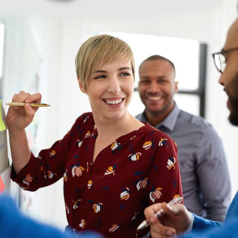 Weilburg Workshop-Szene: Frau am Flipchart, die mit anderen Teilnehmern diskutiert