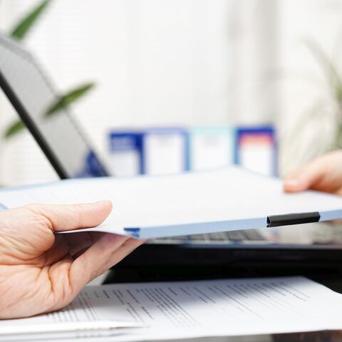 Eine Dokumentenmappe wird über einen Schreibtisch gereicht