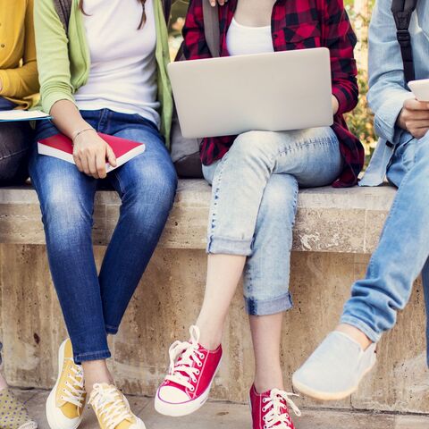 Bild zum Thema Sitzende Jugendliche nebeneinander mit Büchern, Notebooks und Tablets in den Händen