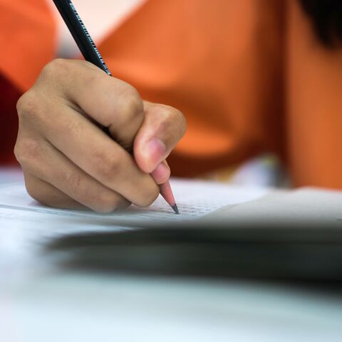 Bild zum Thema Eine Hand mit Stift, die gerade etwas in ein aufgeschlagenes Heft schreibt