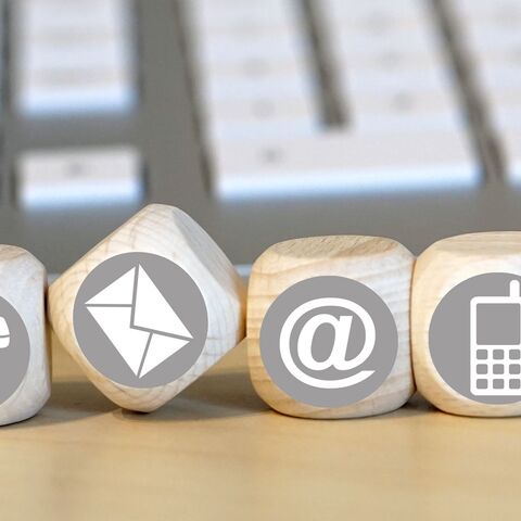 Kontakt Vier Holzwürfel mit Symbolen für Telefon, Briefe, E-Mail und Handy